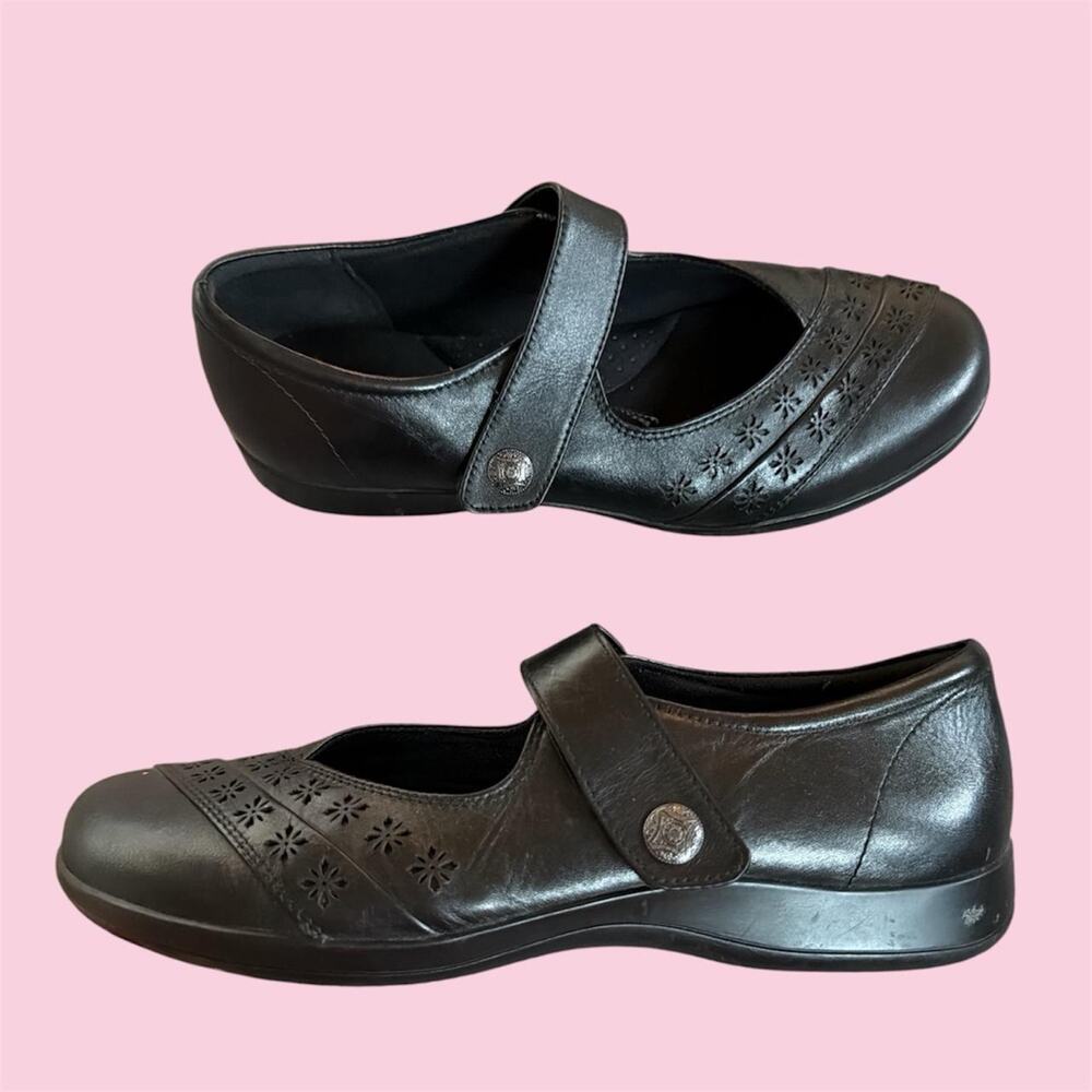 Black leather Mary Jane shoes with floral cutouts and buckle detail